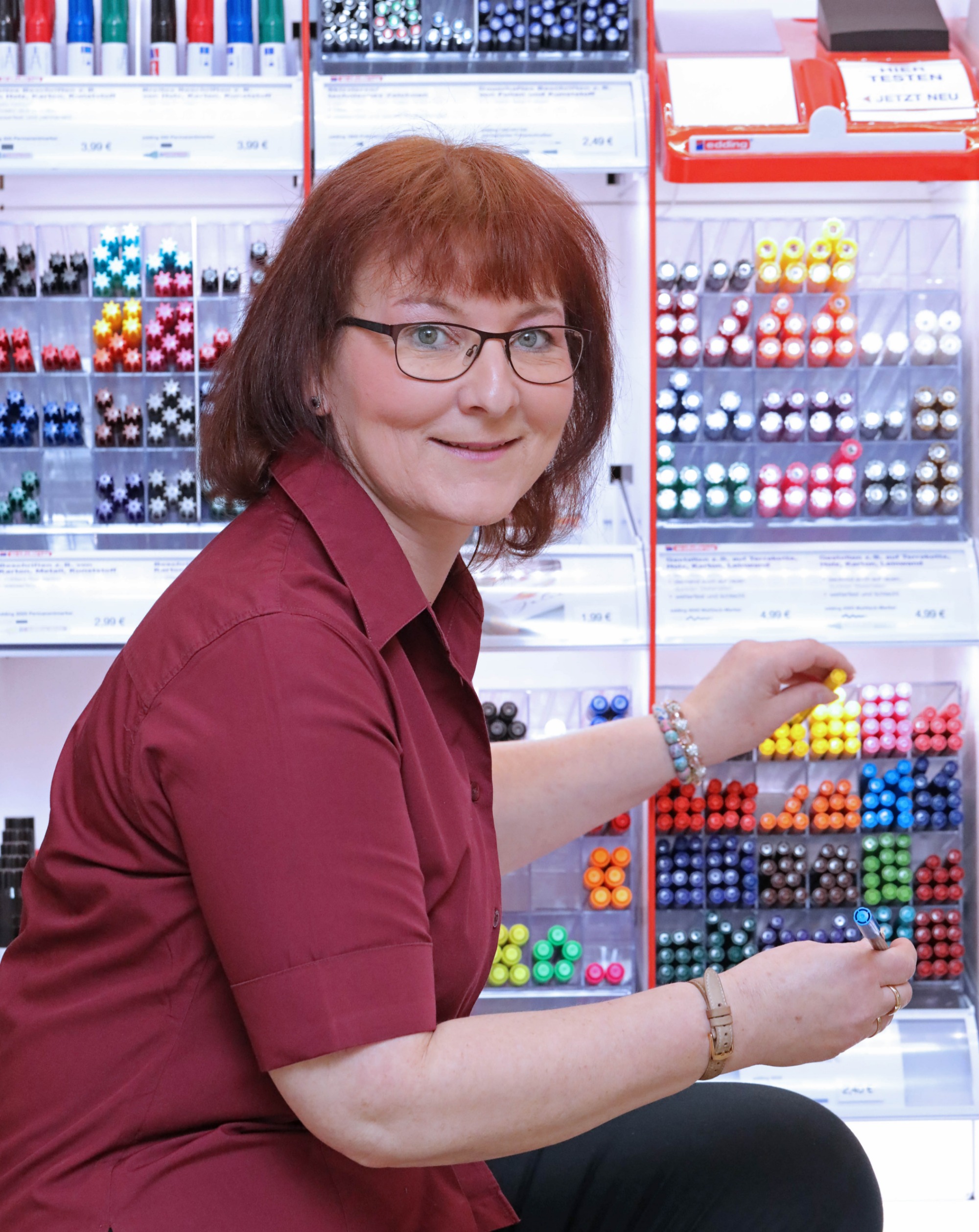 Mitarbeiterin wählt einen Stift aus dem Stabilo-Regal